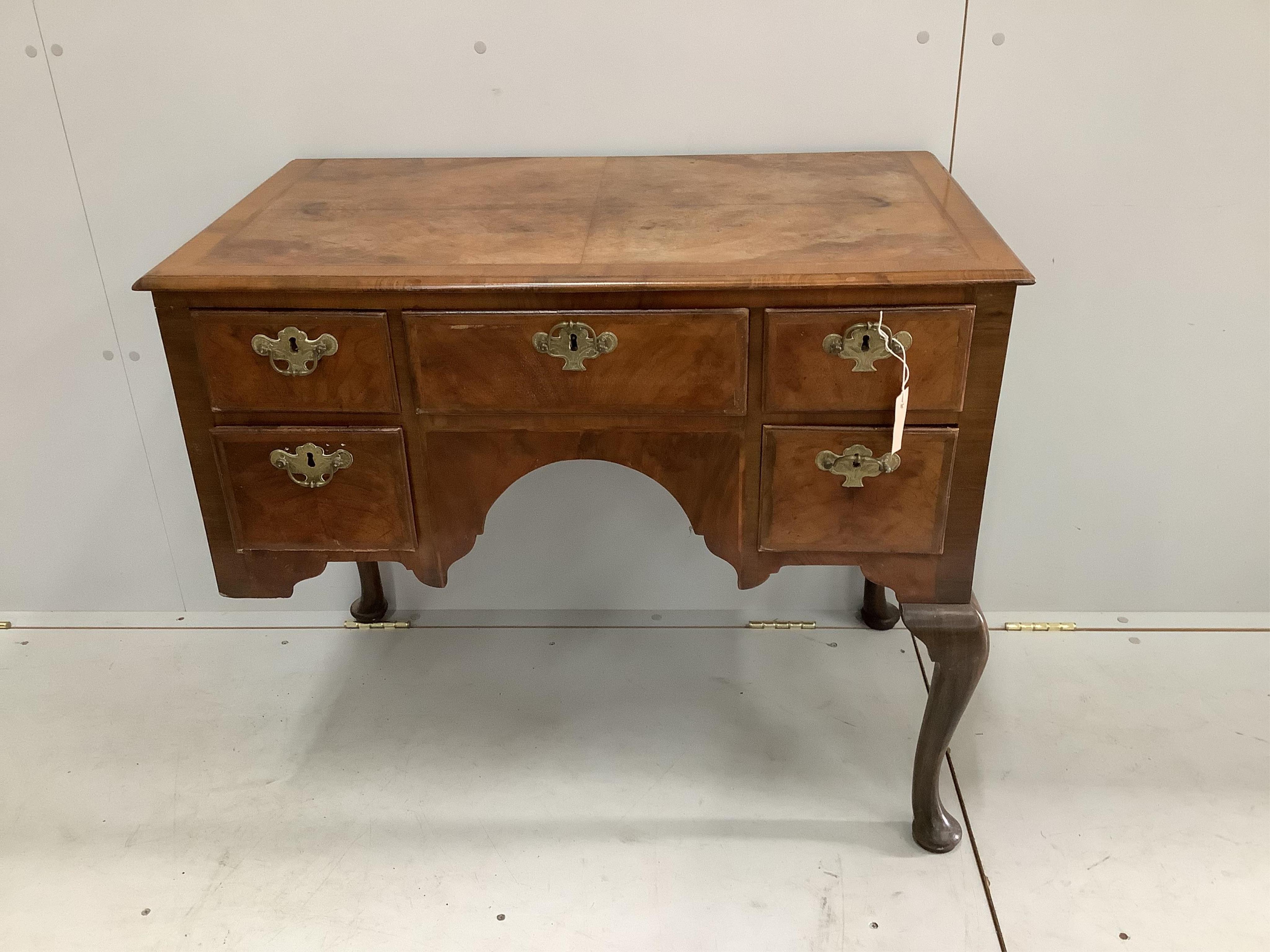 A Queen Anne Revival feather banded walnut kneehole dressing table, width 88cm, depth 50cm, height 75cm. Condition - poor, front leg a.f.